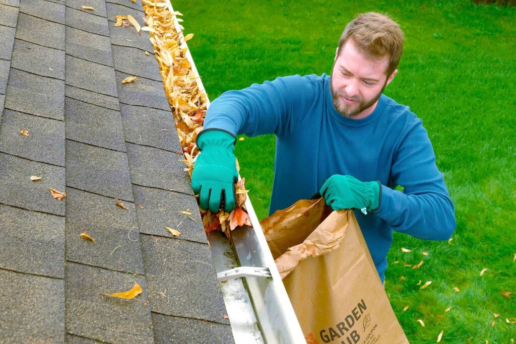 Miami homeowner cleaning debris from residential gutter